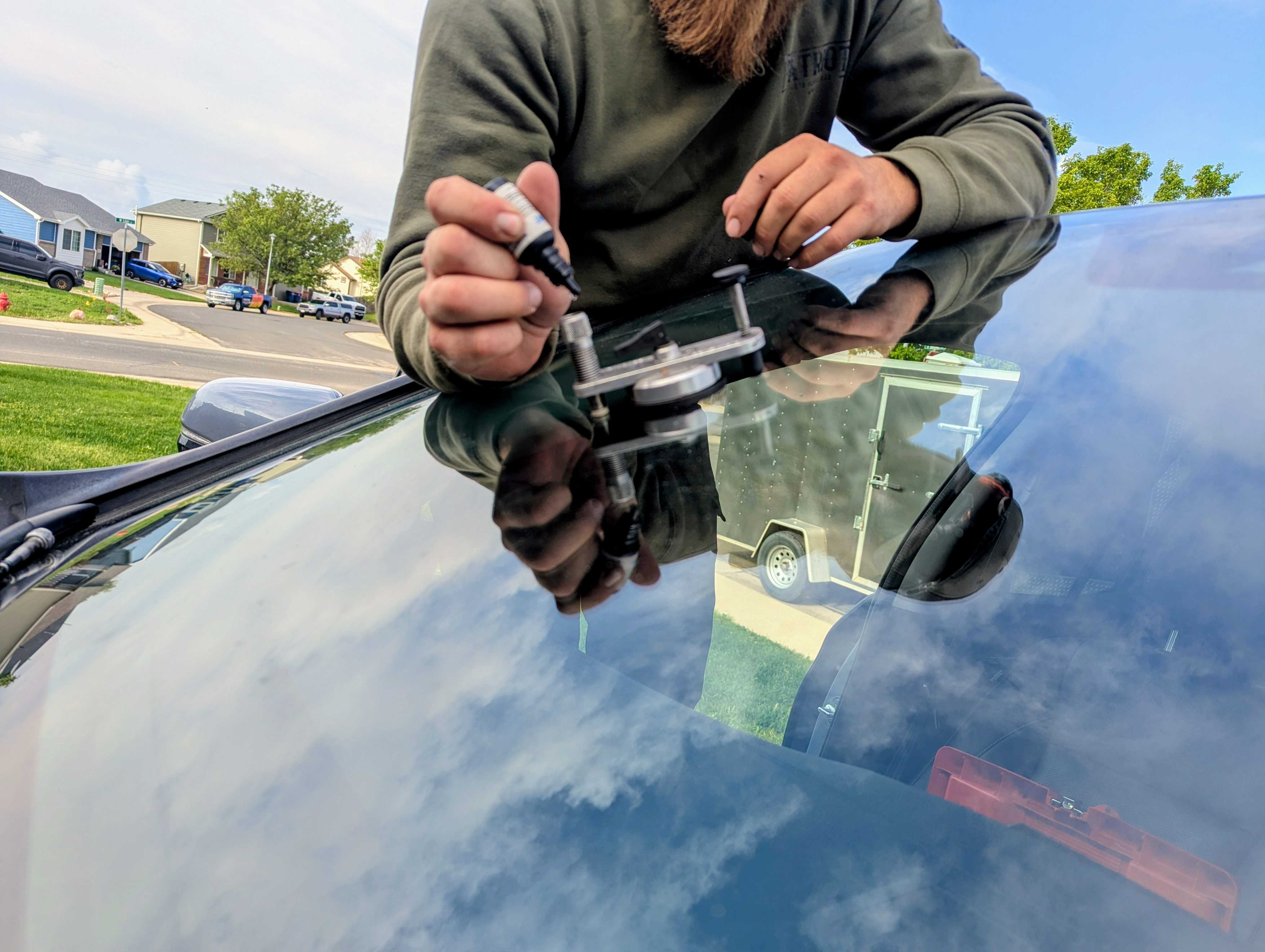 Patriot Auto Glass technician applying resin to a windshield chip with an injector bridge