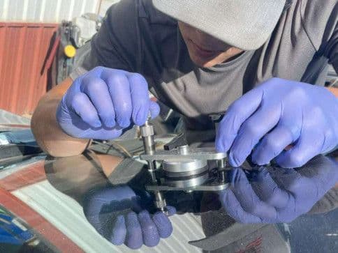 Technician using a chip repair bridge and resin injector on a windshield
